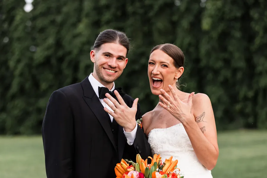 Recién casados mostrando sus anillos de matrimonio, sonriendo