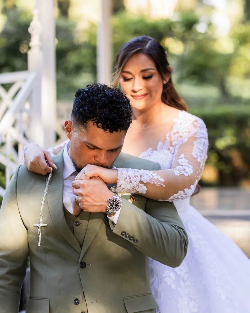 Novio besando la mano de la novia con ternura, ambos sonriendo