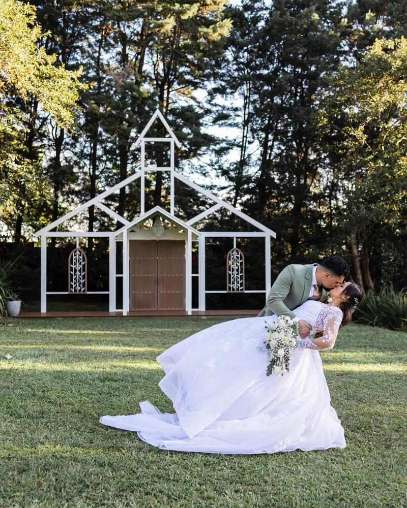 Novios besándose frente a capilla blanca