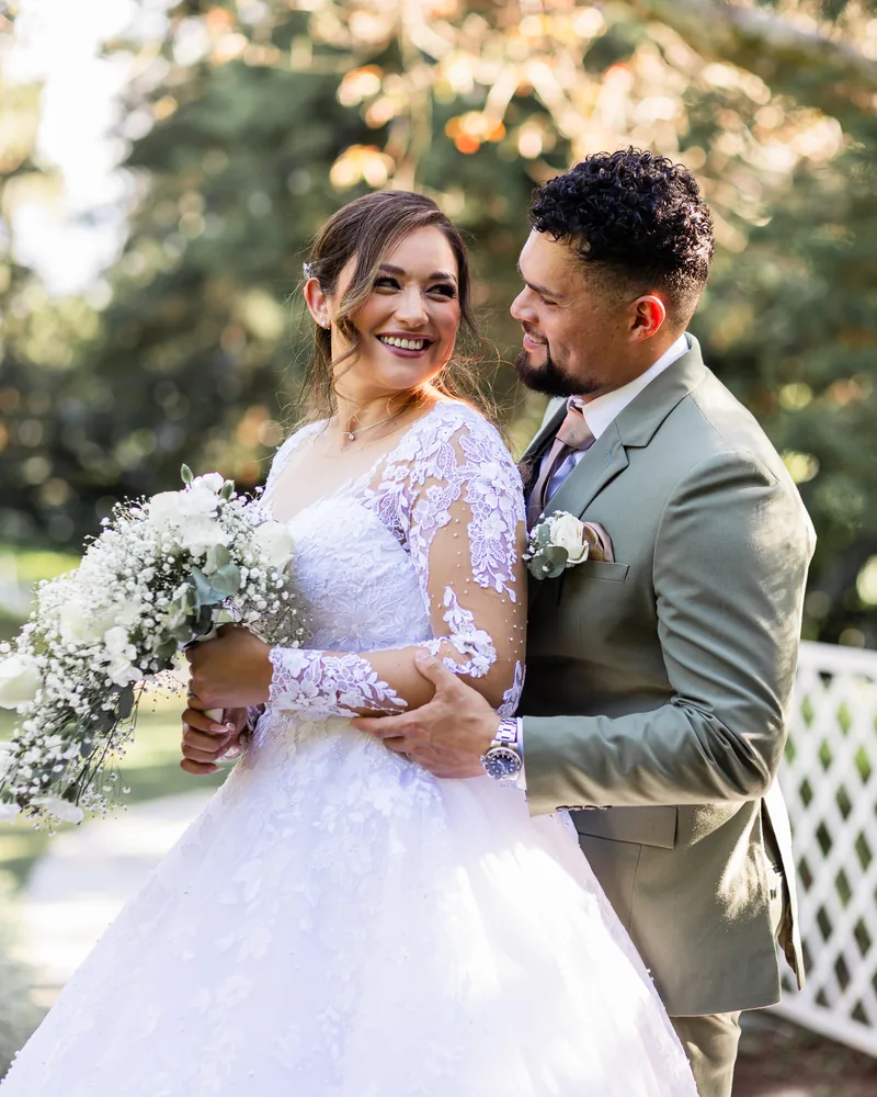 Novios mirándose sonrientes con ramo de flores